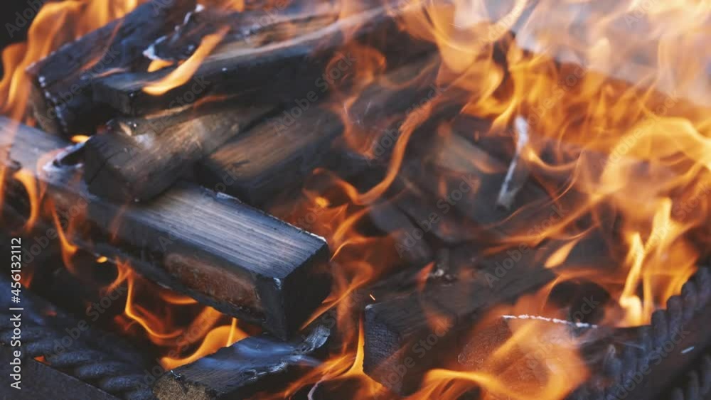 A stack of chopped firewood burns in an old brazier. Close-up. Backyard cooking concept A stack of chopped firewood burns in an old brazier. Close-up. Backyard cooking concept
