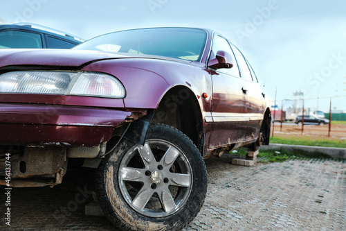 An old rusty machine without a wheel with an inverted axle awaiting repair outside. Vehicle in the open air