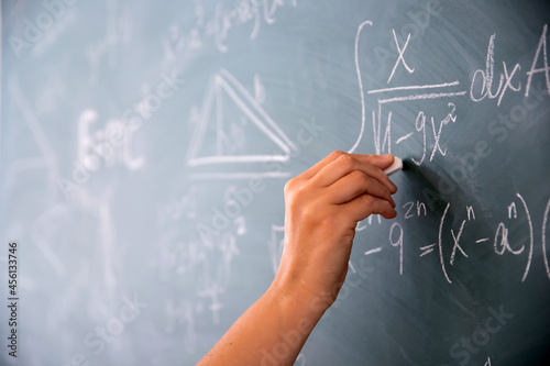 Fototapeta Teacher or student writing on blackboard during math lesson in school classroom