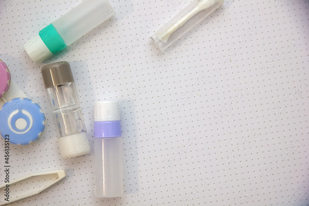 Rigid contact lens on light background with holder, liquid, container, cleanser, tweezers and sucker Rigid contact lens on light background with holder, liquid, container, cleanser, tweezers and sucker