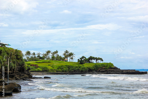A green golf course with plants and palm trees on the coastline in Asia. Field for a game with a view of the sea in Bali, Indonesia