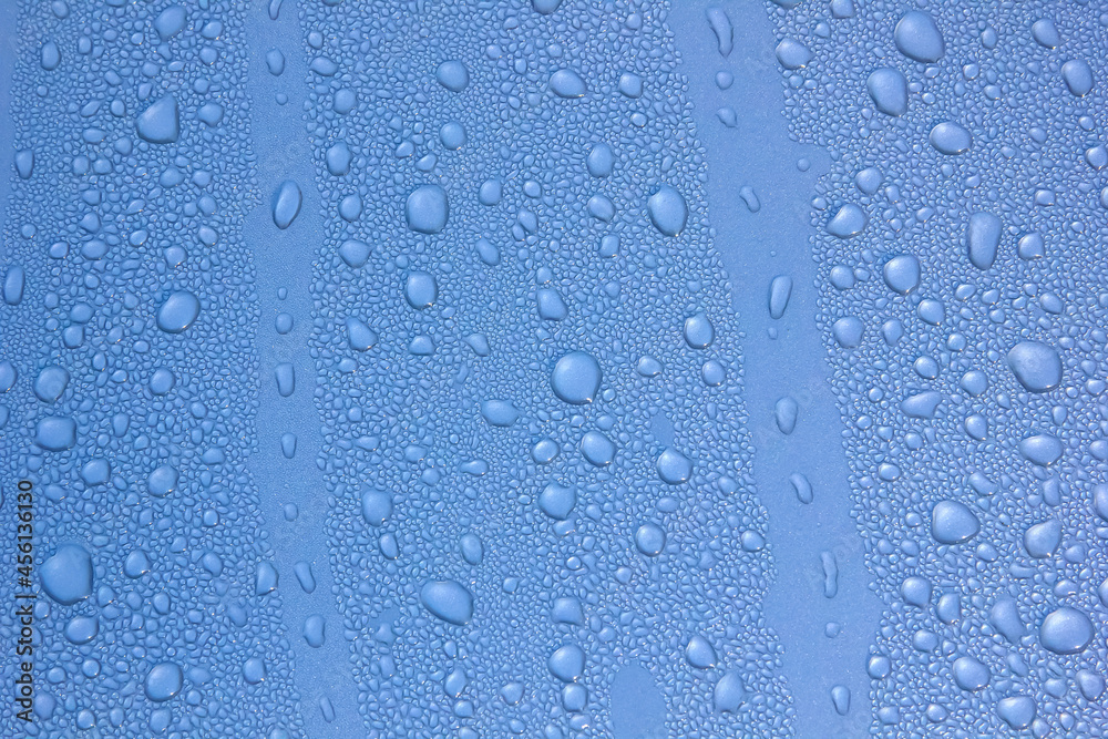 Water drops of morning dew on window glass, smooth surface. Set of condensation droplet  on a blue Background. Texture, abstract background, backdrop