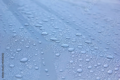 Water drops of morning dew on window glass, smooth surface. Set of condensation droplet on a blue Background. Texture, abstract background, backdrop