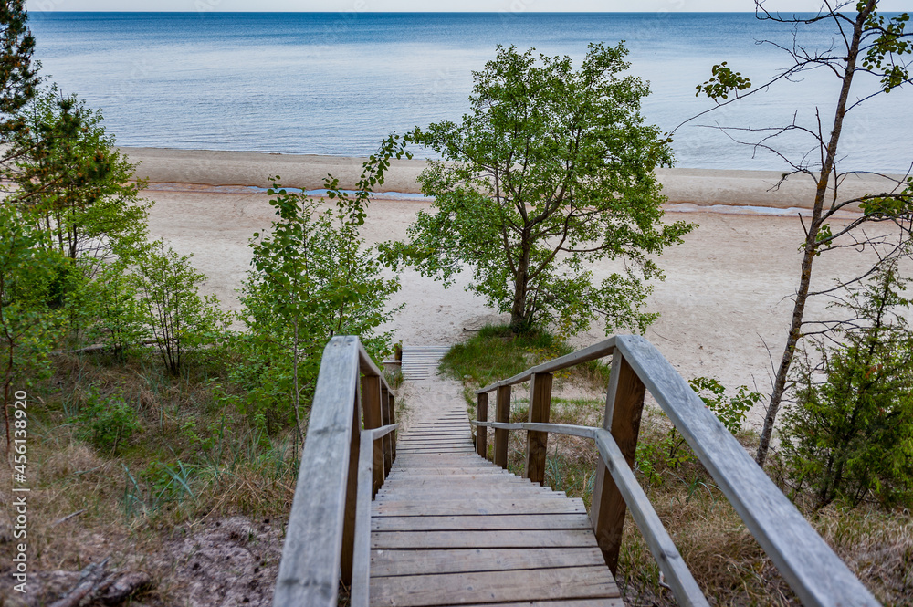 Footbridge over a dune at the beach in Latvia. Baltic Sea. Wooden steps leading to white sand beach. Summer landscape. Evazu Nature Trail.