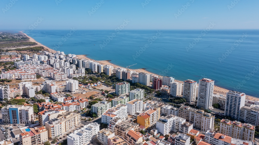 Beautiful aerial cityscapes of the tourist Portuguese city of Quarteira. On the seashore during the beach season with tourists who are sunbathing.