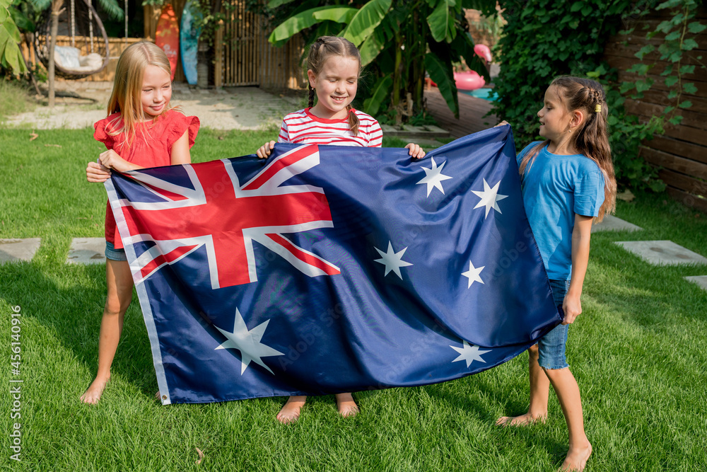 National day of Ausralia. Happy patriot children girls holding waving flag of Australia while celebrating in the backyard on sunny day. Outdoor events with family and kids