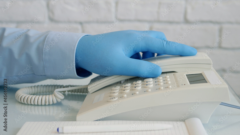 Man Wearing Protection Gloves in Hands Using Telephone. Landline Communication Used in Hospital. Man Wearing Protection Gloves in Hands Using Telephone. Landline Communication Used in Hospital.