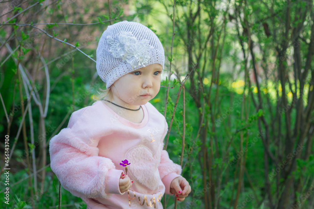 Cute little gentle girl 2 years old in a pink soft jacket walks in the park Cute little gentle girl 2 years old in a pink soft jacket walks in the park