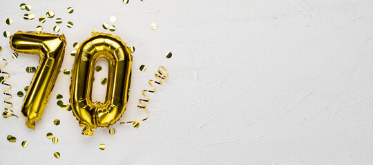 golden foil balloon number seventy. Birthday or anniversary card with the inscription 70. gray concrete background.