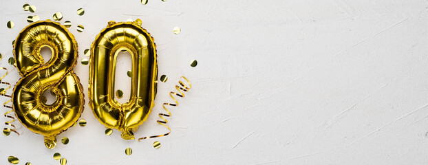 golden foil balloon number eighty. Birthday or anniversary card with the inscription 80. gray concrete background.