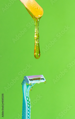 Sugar paste for hair removal against a razor. Sugaring paste drips on a razor on a green background. The concept of epilation, spa, body care