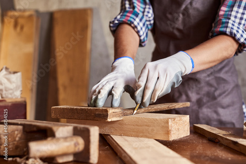 Woman work to making woodcraft furniture in wood workshop. Female carpenter working in carpentry shop with pencil drawing sign on plank. Girl professional high skill workman.
