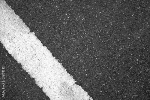 Surface rough and wet of asphalt after the rain, Grey with white line on the road and small rock, Texture Background, Top view © Jomic