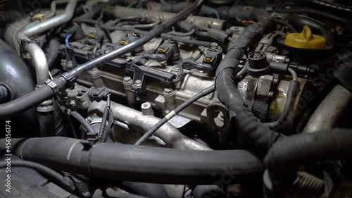 Close up view of old car engine running under artificial lights. Diesel motor. Macro shot of the inside of the car, engine from the vehicle is in car repair shop. Slow motion, low angle