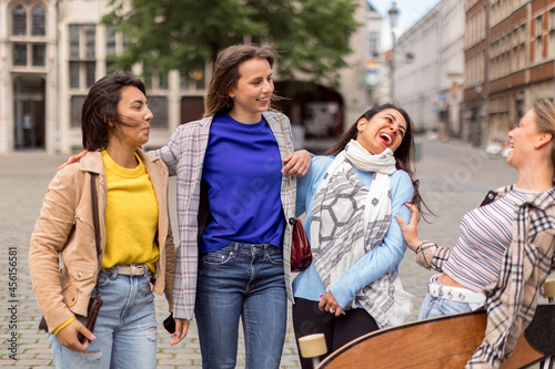 four young women friends laugh carefree in the city center - focus on Indian woman face on the right