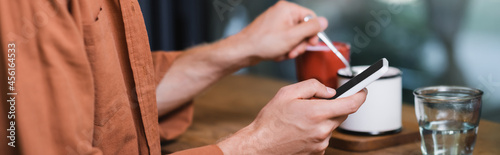 cropped view of man texting on smartphone in cafe  banner