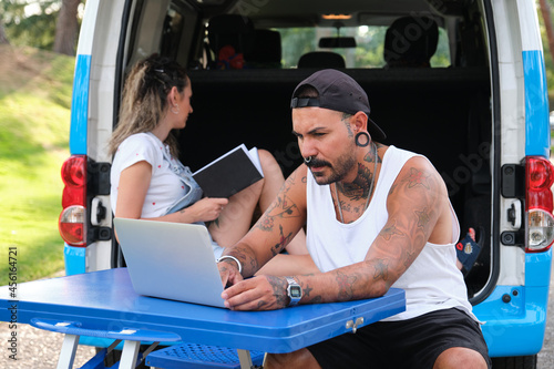 Young tattooed couple reading and working in the back of the van.