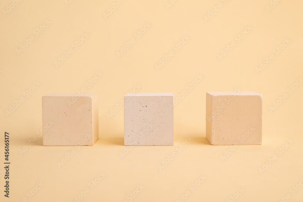 Three concrete cubes on a beige abstract background. geometric podium. Empty showcase for the presentation of cosmetic products. Three concrete cubes on a beige abstract background. geometric podium. Empty showcase for the presentation of cosmetic products.