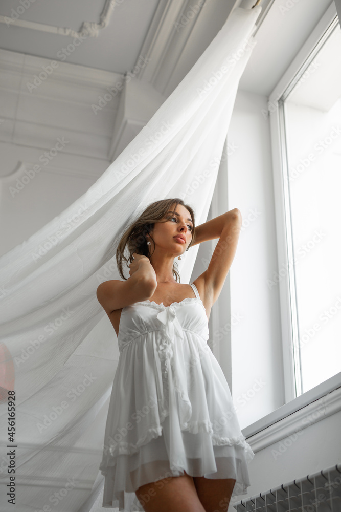 beautiful gentle image of the bride in a white peignoir with makeup near the window beautiful gentle image of the bride in a white peignoir with makeup near the window