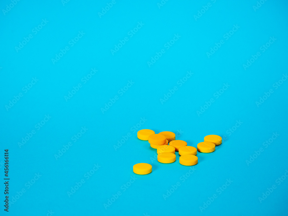 Yellow pills on blue background with copy space for text. Healthy and medicine. Pain management. Drug abuse in teenage concept Yellow pills on blue background with copy space for text. Healthy and medicine. Pain management. Drug abuse in teenage concept