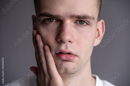 Obraz na płótnie Sad Young Guy Teen Holding A Face. toothache w salonie