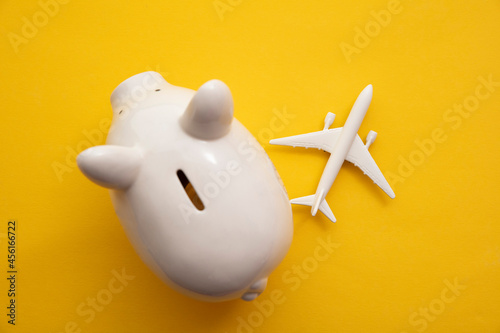 Holiday flight fare saving concept. Piggy bank with a toy plane. Vacation budget planning