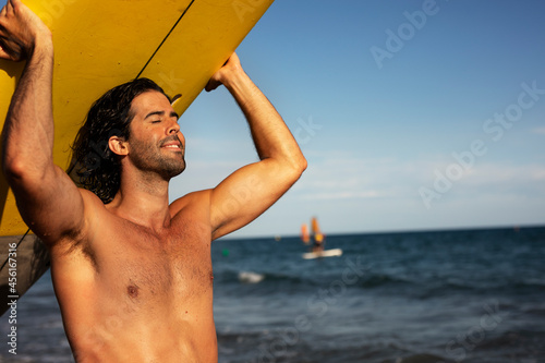 Handsome man with surfboard. Surfer taking a break on the beach