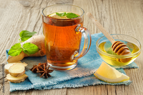 Ginger tea with lemon and mint in glass cup at blue table-napkin.