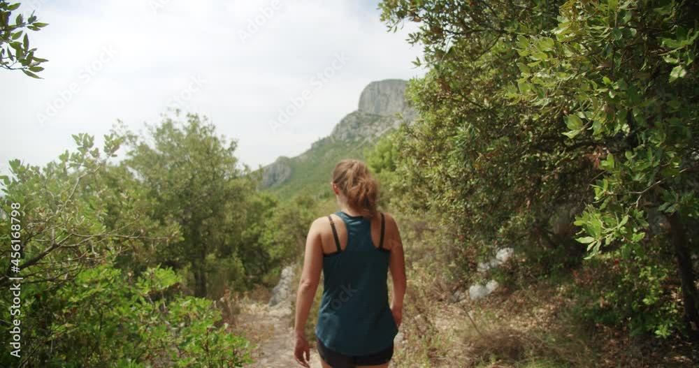 A young lady walking through a forest mountain path in the sun, slow motion. A young lady walking through a forest mountain path in the sun, slow motion.