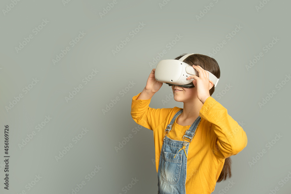 Child girl playing virtual reality over grey background, digital technology concept, innovative technologies Child girl playing virtual reality over grey background, digital technology concept, innovative technologies