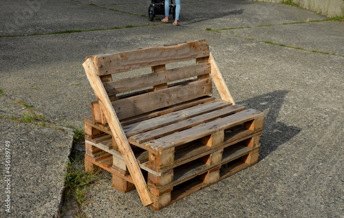 bench made of returnable pallets for goods. it has a back and seat made of wooden planks. stands on a concrete surface in the park on the square photo