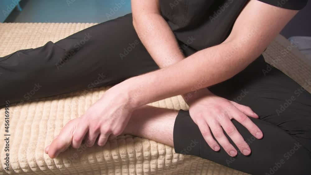 Caucasian young man doing foot self-massage. A professional masseur demonstrates the correct implementation of massage of the surface of the foot Caucasian young man doing foot self-massage. A professional masseur demonstrates the correct implementation of massage of the surface of the foot