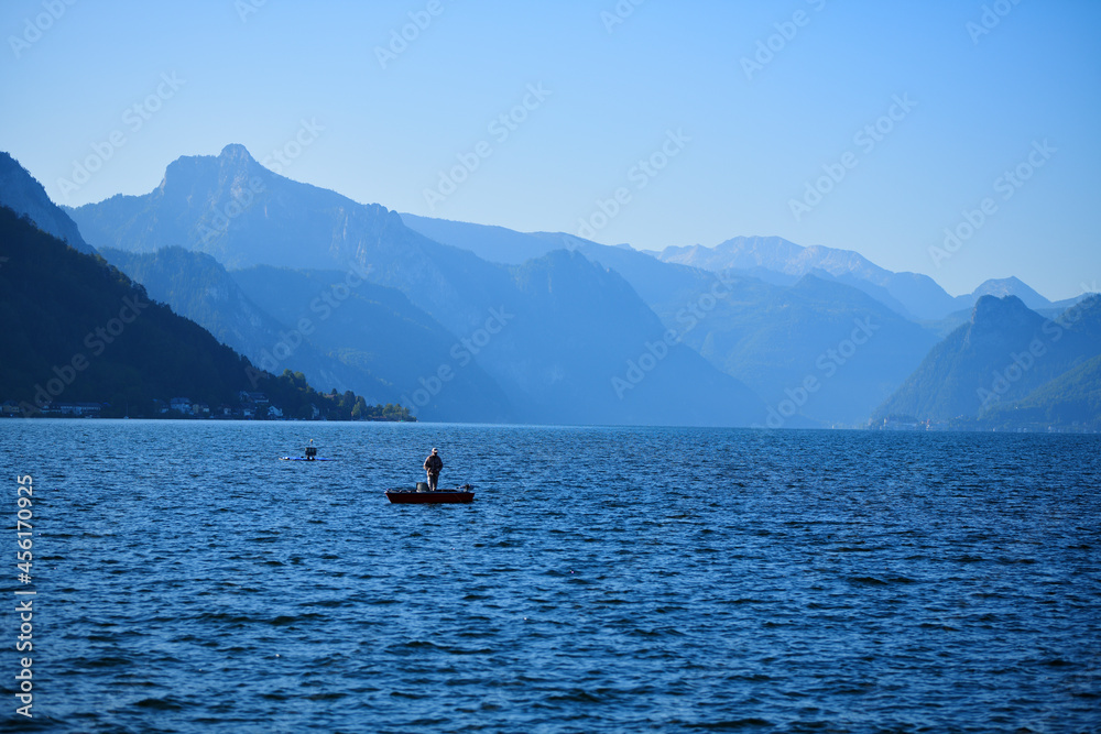 Ein Angler im Boot einsam auf einem See in den Bergen