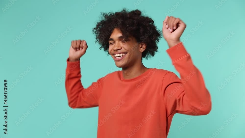 Slow motion fancy young curly african american man 20s wears azure t-shirt dance fool around have fun gesticulating with hand enjoy relax isolated on plain pastel light blue background studio portrait Slow motion fancy young curly african american man 20s wears azure t-shirt dance fool around have fun gesticulating with hand enjoy relax isolated on plain pastel light blue background studio portrait