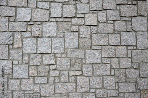 irregular cyclopean masonry on the wall of a house or cottage. Gray granite is cut into cube shapes joined by cement.