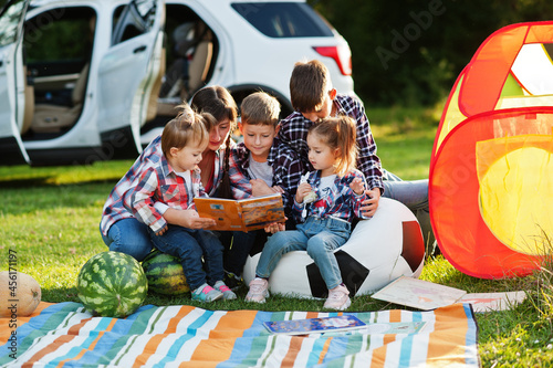 Family spending time together. Mother reading book outdoor with kids against their suv car. © AS Photo Family