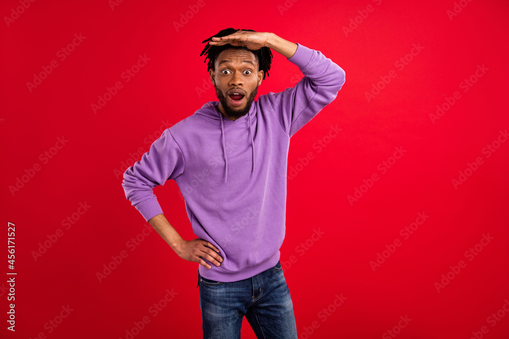 Fototapeta premium Photo portrait man with dreadlocks amazed looking far hand near forehead isolated vibrant red color background