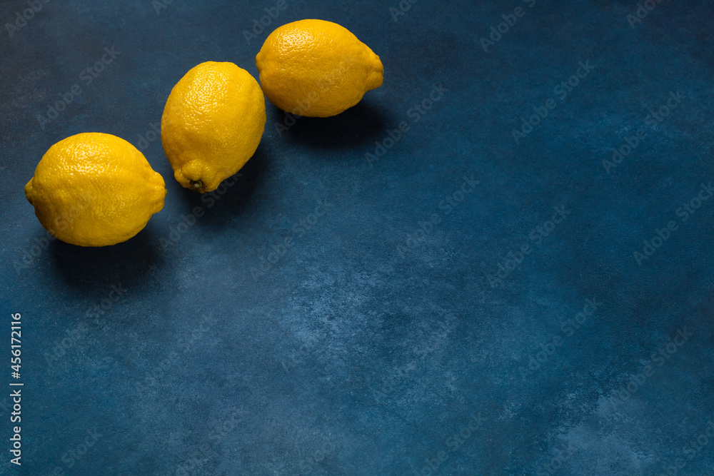 Three bright yellow citrus fruits on a blue background top view Three bright yellow citrus fruits on a blue background top view