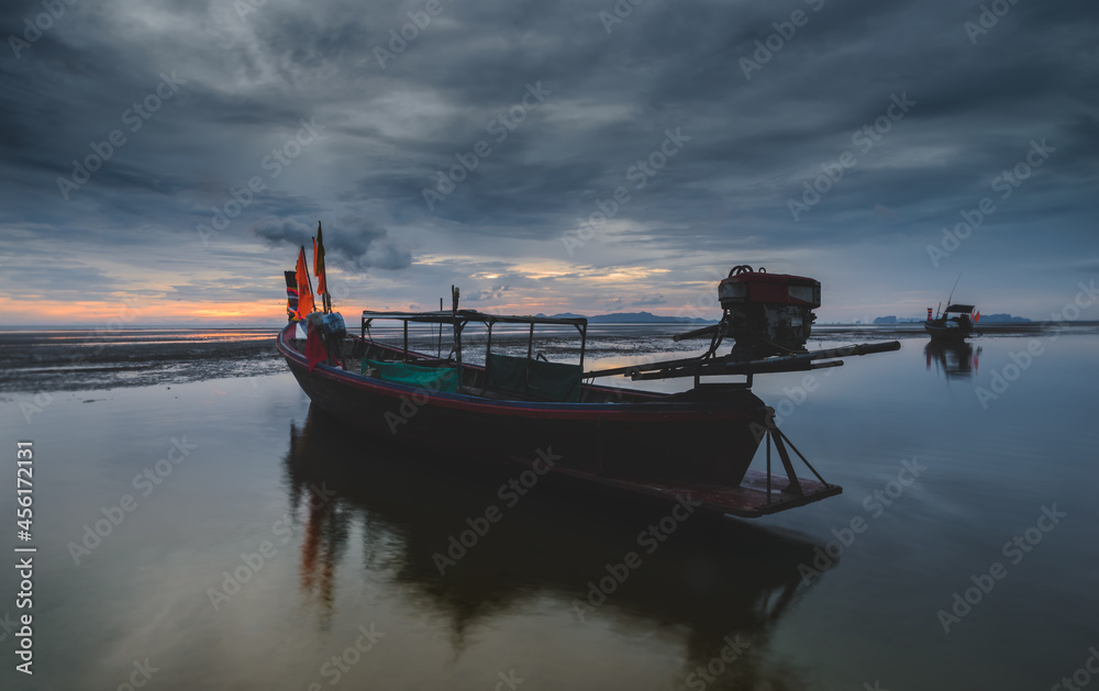 Obraz premium Fishery wooden boat with sunset sky low lighting.