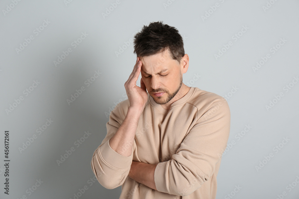 Man suffering from terrible migraine on light grey background Man suffering from terrible migraine on light grey background