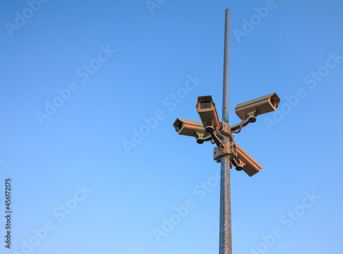Column surveillance cameras on clear blue background, copy space