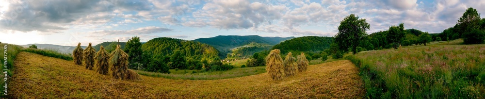 Panorama with piles of hay in the mountains. Morning with fog in the valley. Panorama with piles of hay in the mountains. Morning with fog in the valley.