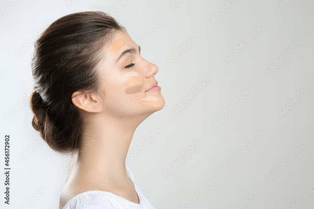 Beautiful girl on light grey background. Using concealers and foundation for face contouring Beautiful girl on light grey background. Using concealers and foundation for face contouring