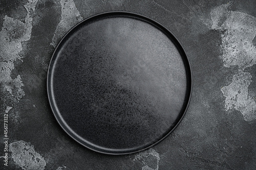 Empty black plate, on black dark stone table background