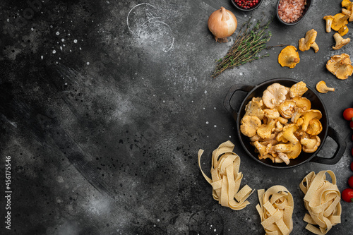 Raw tagliatelle with chanterelle mushrooms ingredients, on black rustic table background, top view flat lay, with copy space for text