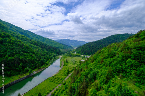 Up view of a valley with a river in Romania. Big forest on a hill. 