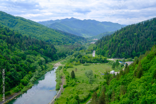 Up view of a valley with a river in Romania. Big forest on a hill. 