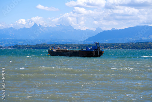 Lake Geneva on a sunny and windy summer day with transport ship and European Alps in the background. Photo taken August 28th, 2021, Nyon, Switzerland.