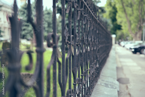 Old iron fense in the city park, close up.