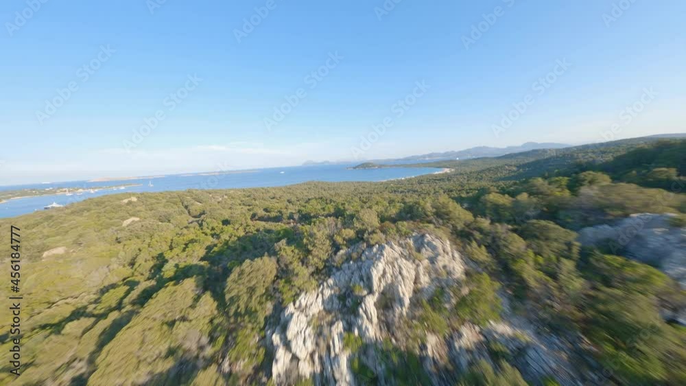 FPV video, view from above, aerial view from an FPV drone flying at high speed over some mountains and green hills with a beautiful sea in the distance. Liscia Ruja, Sardinia, Italy. FPV video, view from above, aerial view from an FPV drone flying at high speed over some mountains and green hills with a beautiful sea in the distance. Liscia Ruja, Sardinia, Italy.